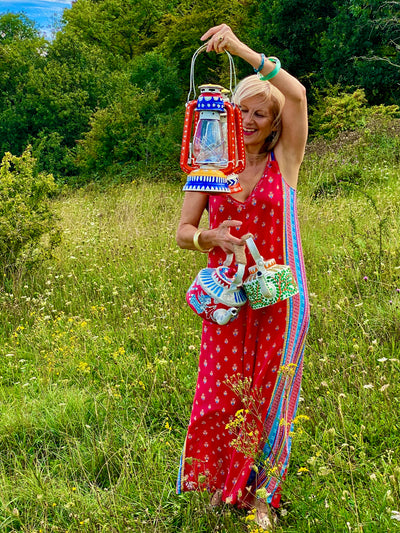 Suzie Bidlake holds up hand-painted Indian lanterns and kettles while walking in a field